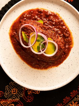 La chancla poblana, bañada en adobo rojo con cebolla y aguacate