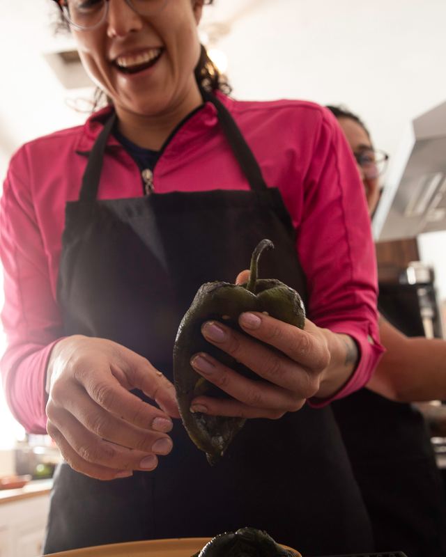 Una cocinera pela un chile poblano recién tatemado, todavía humeante