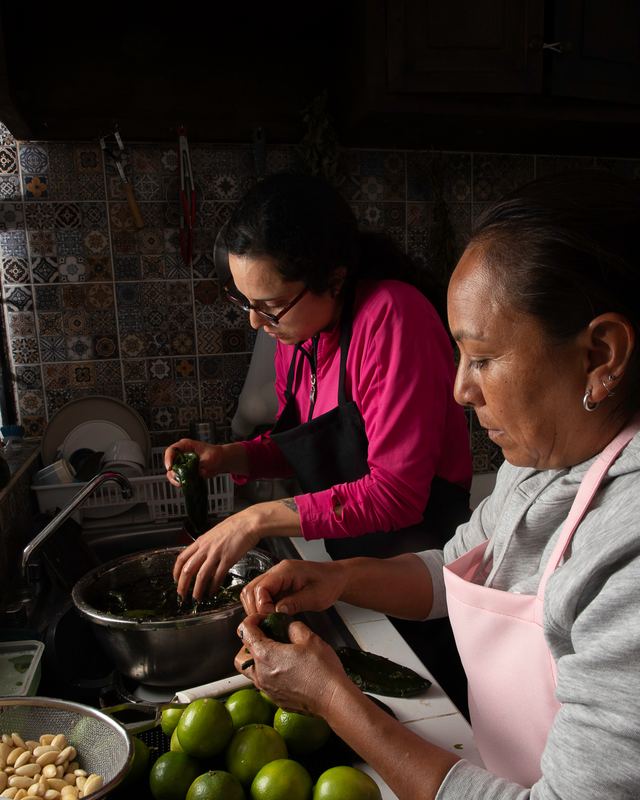 Dos cocineras pelando la nuez, mitad por mitad, junto a los limones