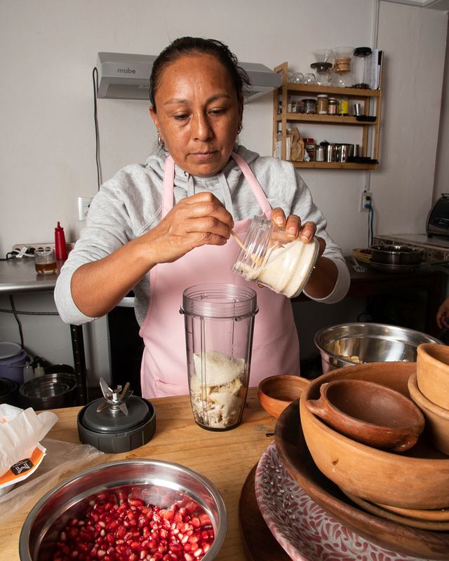 Una cocinera vierte la leche en la licuadora para moler la nogada