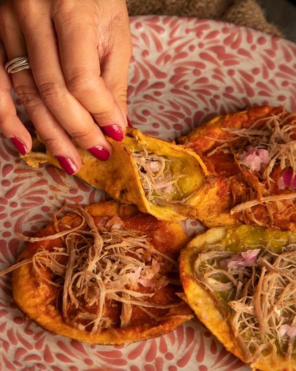 Unas manos sirven las chalupas sobre un plato rosa