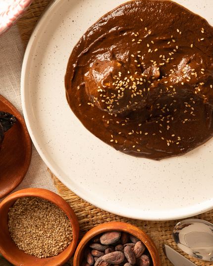 El mole poblano servido, con cacao, ajonjolí y chiles secos alrededor